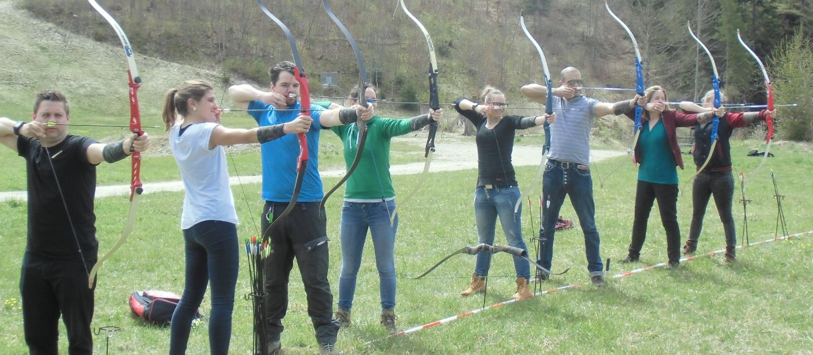 Gruppe beim Bogenschießen im Freien als Firmenevent